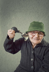 Elderly woman squeezing horn into her own ear.