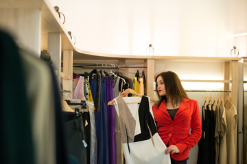 Woman shopping choosing dresses looking in mirror uncertain