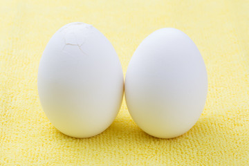 Two cracked eggs on yellow background