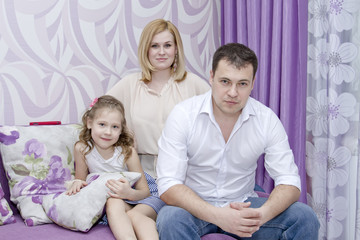 Happy young parents with  daughter in a lilac room