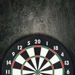 Darts board against vintage dark background. Cracked texture
