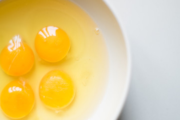 Four yellow egg yolks in a white bowl.