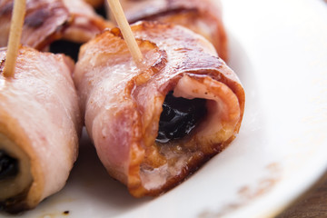 Baked prunes in bacon on a plate