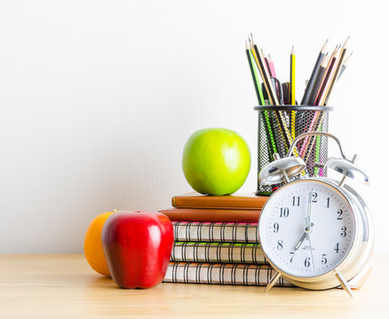 Back to school , note book , clock , pencil , apple on wood tabl