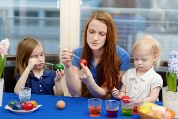 Mother and her daughters painting Easter eggs