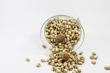 Viele Pistazienund 2 Wallnüsse fallen aus einer Glasschale