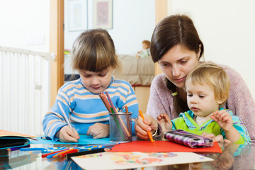 serious mother and children sketching with pencils