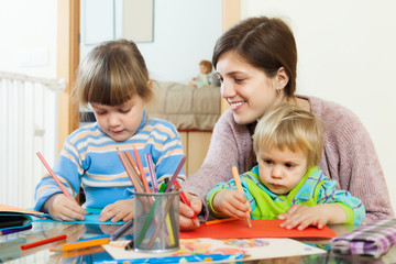 Happy mother and children sketching with pencils