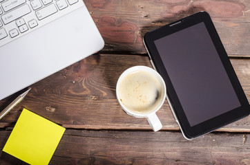 Tablet with blank screen and coffee cup on wooden table