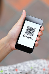QR coupon on mobile display holding by woman hand