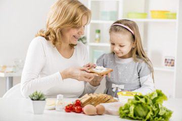Cute little girl with Grandmother making a Sandwich.