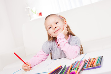 Cute little girl drawing colored pencils at home.