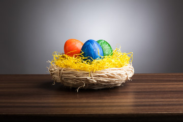 Easter nest with colored eggs on table, gray background