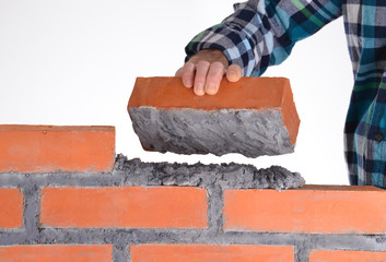 Constructor sujetando un ladrillo construyendo un muro.