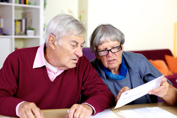 Senior couple reading bills at home
