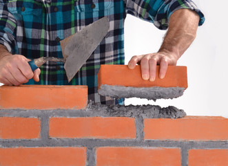 Constructor sujetando un ladrillo construyendo un muro.