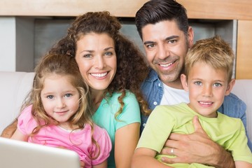 Happy family sitting on sofa with laptop
