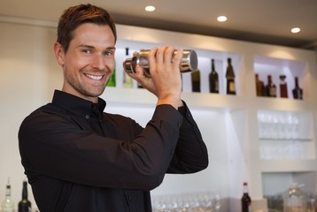 Smiling bartender shaking cocktail