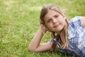 Fototapeta premium Cute young girl lying on grass at park