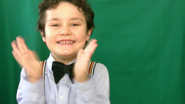 Boy clapping in front of a green screen