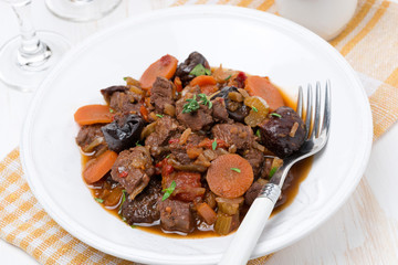 Stew with beef and vegetables on the plate, top view