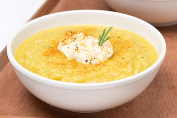 vegetable cream soup with cream and rosemary on a wooden tray