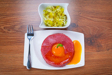 Tasty steak tartare on the plate with egg yolk