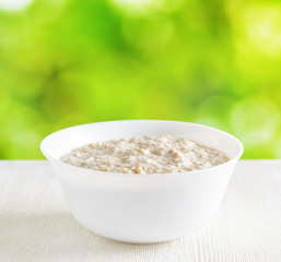 Bowl of oat porridge on nature background