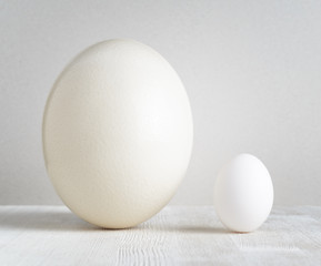 Ostrich egg and chicken egg on white table