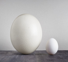 Ostrich egg and chicken egg on black table