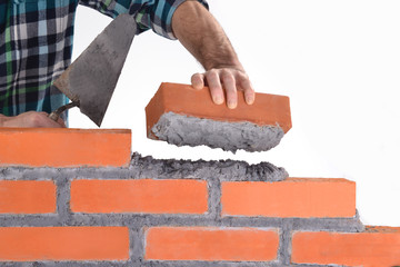 Constructor sujetando un ladrillo construyendo un muro.