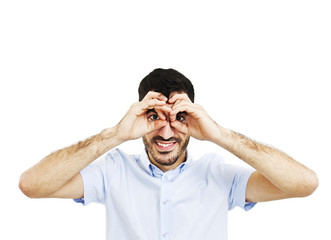 Naklejka premium Handsome young man smiling, making binoculars with his hands