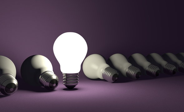 Standing light bulb in row of lying ones on violet