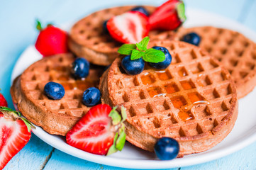 Whole grain waffles with berries on blue wooden background