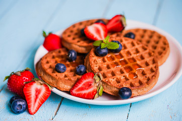 Whole grain waffles with berries on blue wooden background