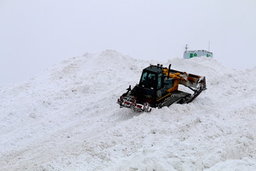 ビルほどの雪堆積場を整備するブルドーザー