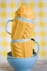 Two blue cups in yellow sweater on a fabric background