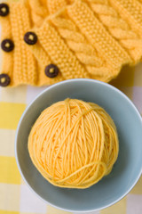 Yellow ball of yarn for knitting in blue plate and pattern