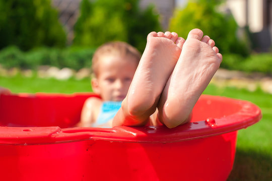 Closeup of little kid's legs in small red pool