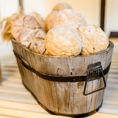 Variety of bread in basket on wooden shelf.