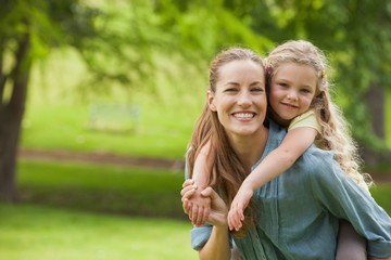 Obraz premium Portret kobiety niosącej dziewczynę w parku