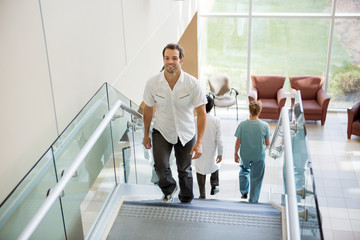 Patient And Medical Team Walking On Stairs In Hospital