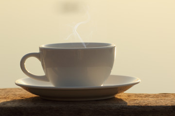 Afternoon coffee cup on wooden board with golden light effect