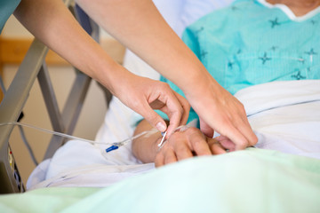 Obraz na płótnie Canvas Nurse Attaching IV Drip On Male Patient's Hand