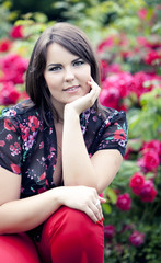 beautiful girl in summer garden near blooming rosebush