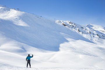 Lone skier waving on a snowy mountain peak