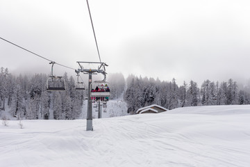 Fototapeta na wymiar Ski lift with passengers in the chair