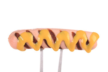 Grilled sausage on a fork with mustard.