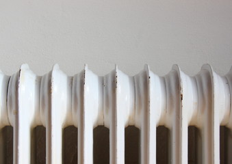Closeup on worn radiator with white wall background