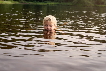 Fototapeta premium Boy swimming in a lake late afternoon